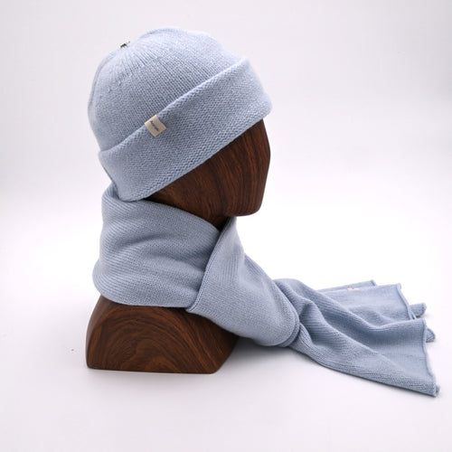 A person wearing a ice blue cuffed beanie with a matching classic scarf.