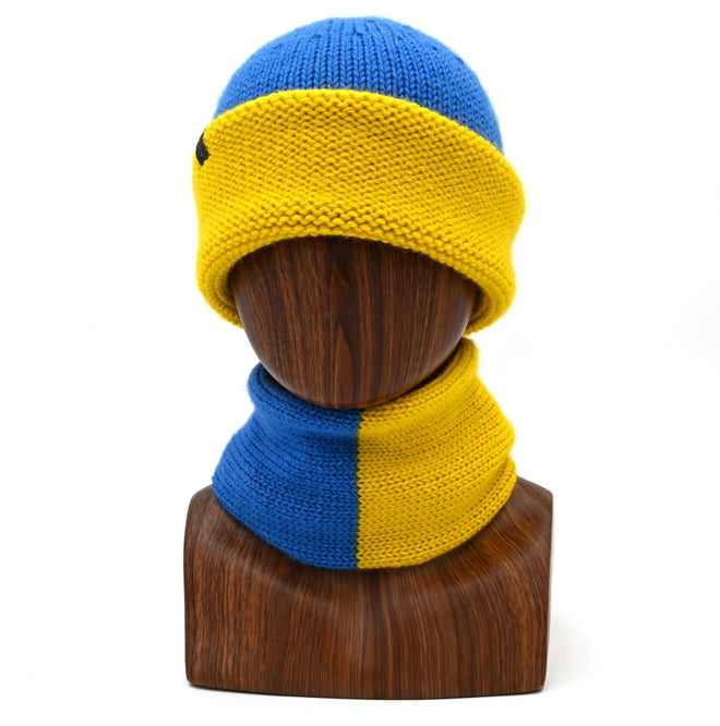 A mannequin wearing a marbled Cuffed Toque in the gold and blue. The Toque features a silver bean at the crown. This is shown here with a matching Cowl