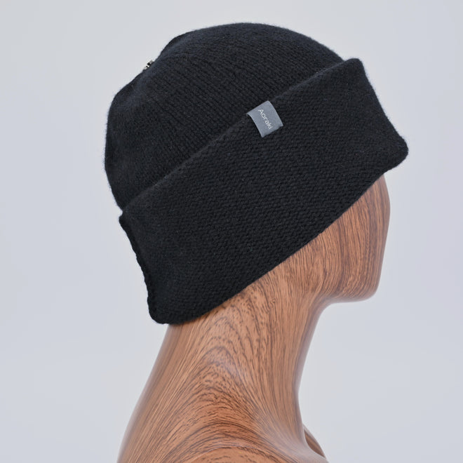 Ebony knit Pashm Beanie on a wooden mannequin head against a light gray background