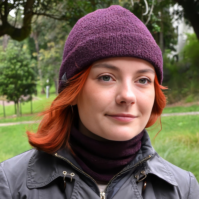 A model wearing a Plumb Milford All-weather toque knitted from 100% merino wool with a waterproof lining, perfect for the outdoors. Paired with a matching Active Infinity Cowl.