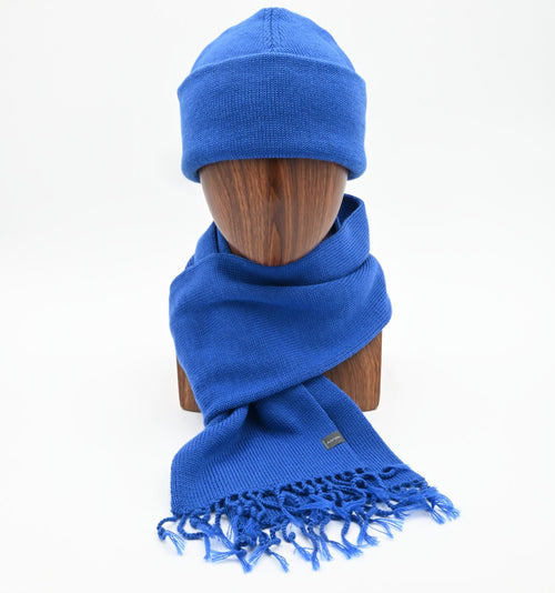 mannequin wearing an azure blue cuffed toque with a matching tassel scarf.