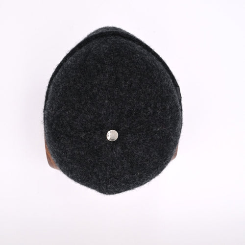 Top view or a gunmetal felted toque with a silver bean on a white background