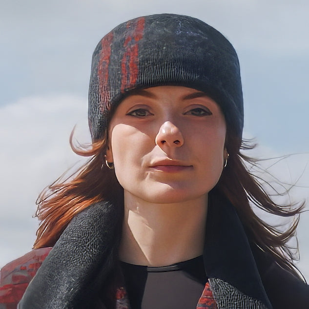 A model wearing a Tri-Stripes RGB felted toque with a cuffed design, a matching Tri-Stripe Felted 1800 Scarf standing near the Manukau Harbor.