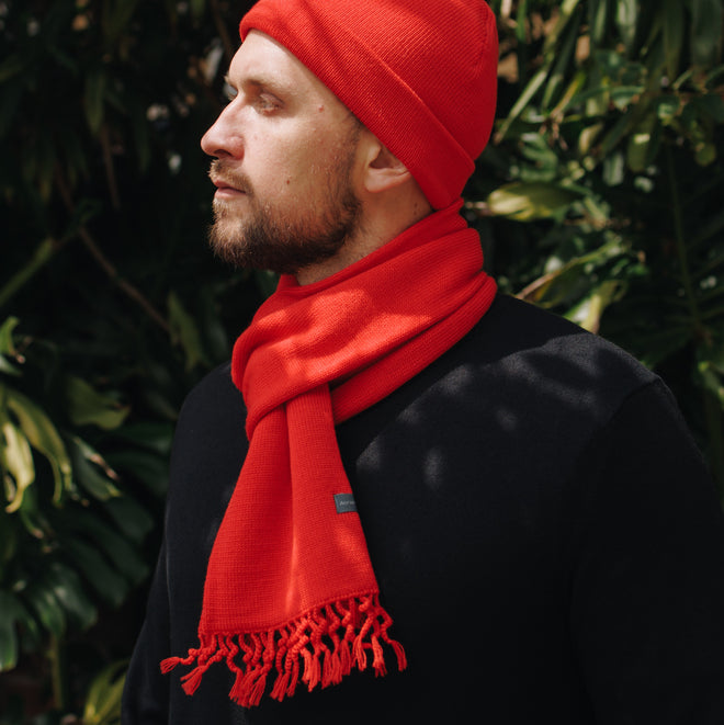A model wearing a Wanaka Fringe Scarf in Poppy. Featuring a distinctive tassel fringe