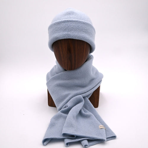 A person wearing a ice blue cuffed beanie and a matching classic scarf.