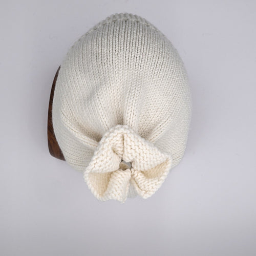 Over head of a mannequin wearing a French Vanilla merino wool Beanie with a distinctive 'petal gather' at the crown hiding the distinctive silver bean at the crown.