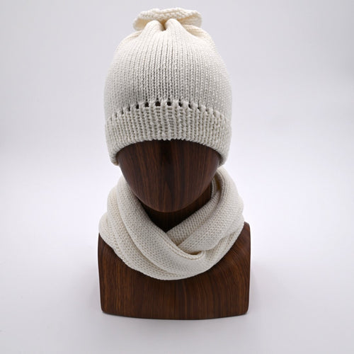 Mannequin wearing a French Vanilla -colored merino wool beanie with a distinctive 'petal gather' at the crown, paired with a matching Infinity Scarf.