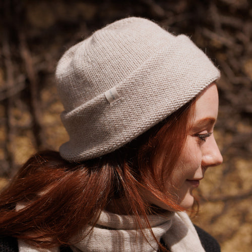 A model wearing an Oatmeal Andes cuffed Beanie and matching Scarf with a subtle pattern, made of Alpaca and Merino wool.