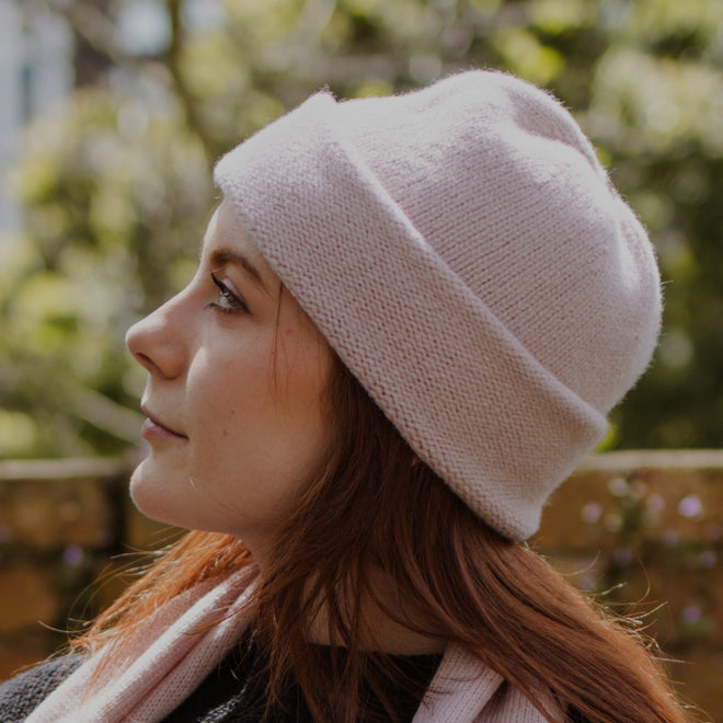 A person wearing a premium pink cuffed beanie in lambswool.